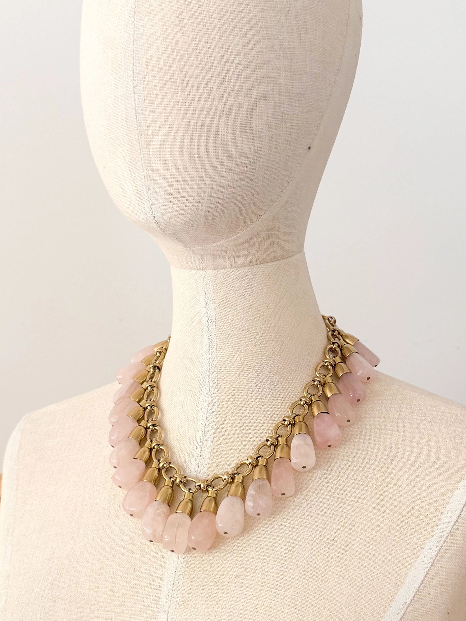 A statement collar necklace featuring a brass chain and links with large dangling rose quartz beads by Canadian designer Michelle Ross