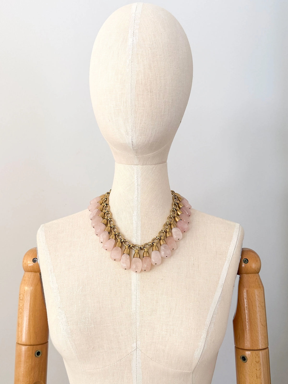 A statement collar necklace featuring a brass chain and links with large dangling rose quartz beads by Canadian designer Michelle Ross