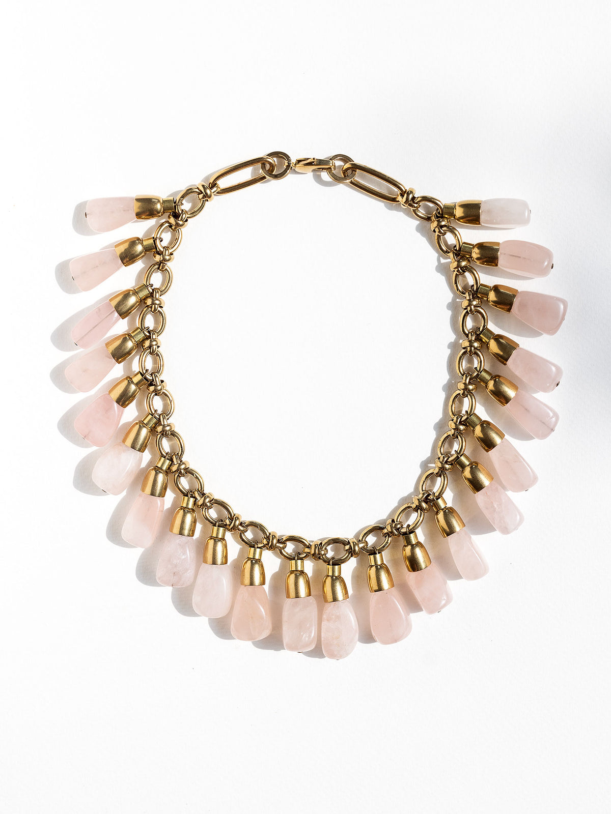 A statement collar necklace featuring a brass chain and links with large dangling rose quartz beads by Canadian designer Michelle Ross