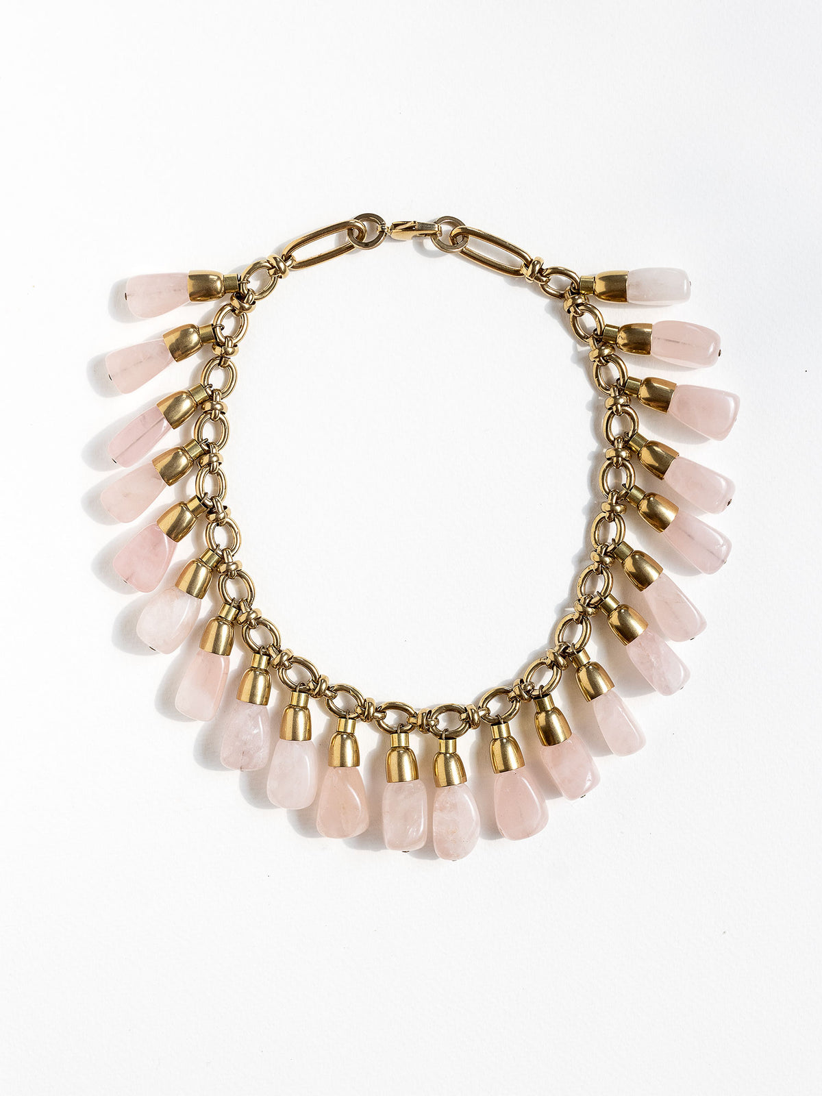 A statement collar necklace featuring a brass chain and links with large dangling rose quartz beads by Canadian designer Michelle Ross