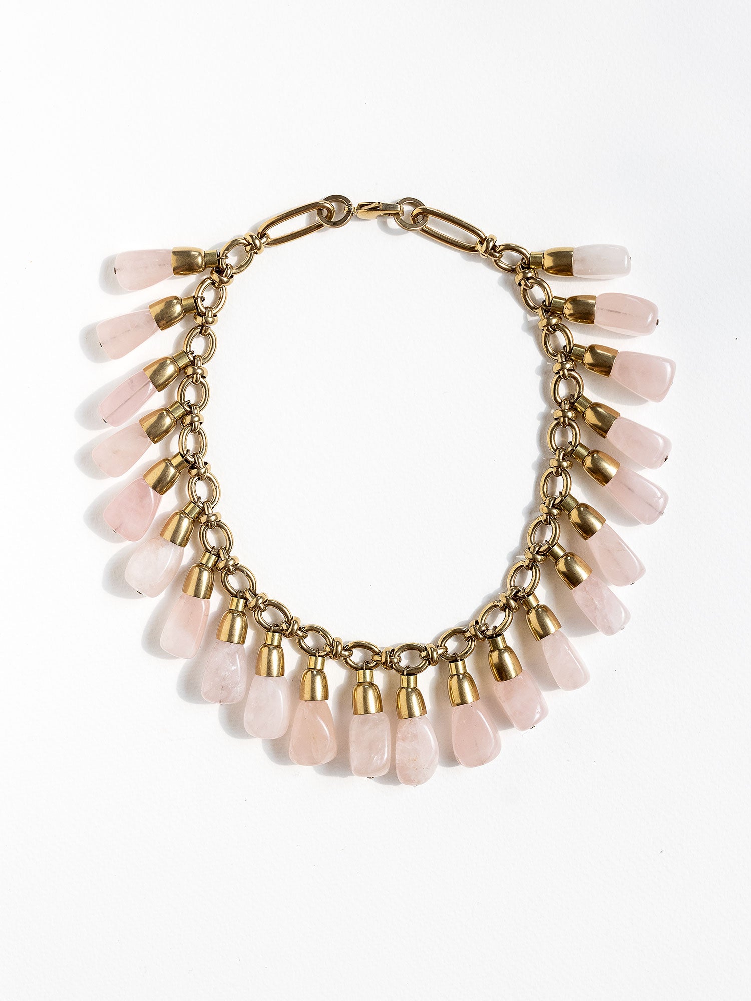 A statement collar necklace featuring a brass chain and links with large dangling rose quartz beads by Canadian designer Michelle Ross