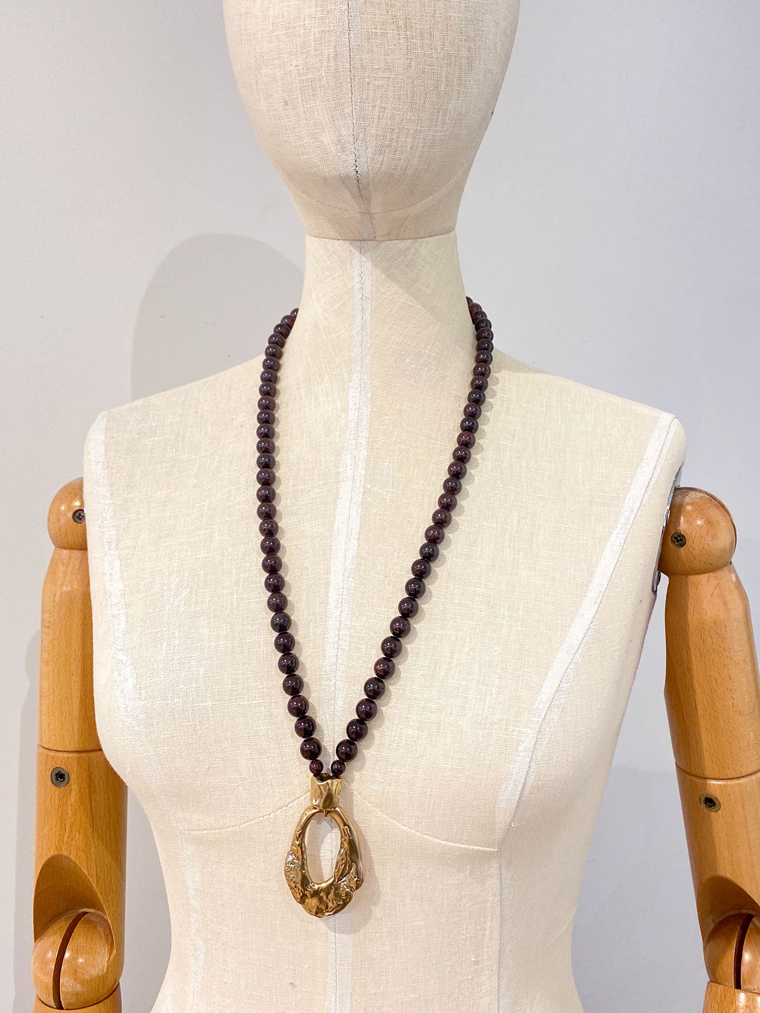 Necklace with garnet beads and brass pendant by Michelle Ross
