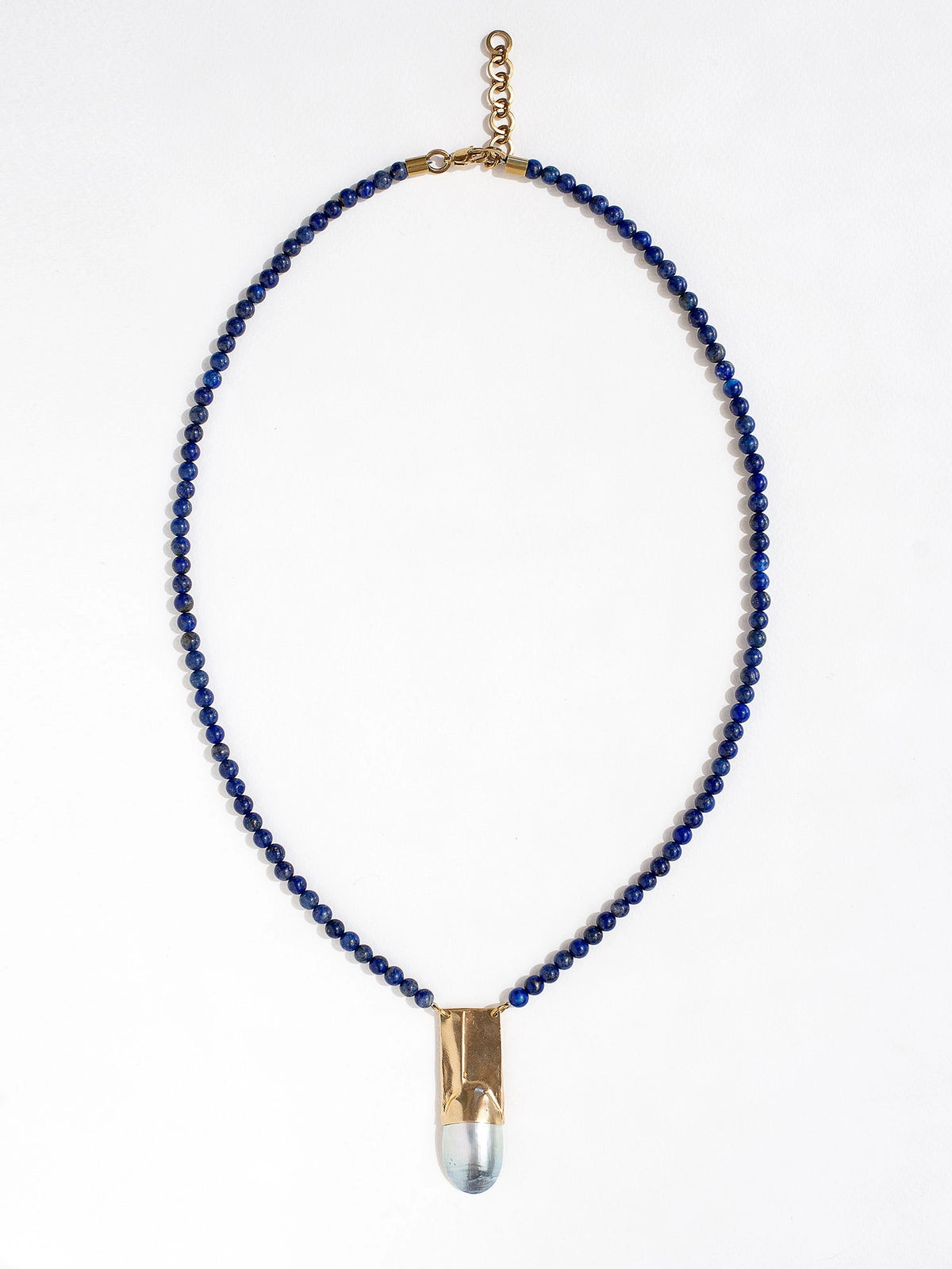 A lapis lazuli beaded necklace with a large statement mother of pearl and brass pendant by Canadian jewellery designer Michelle Ross