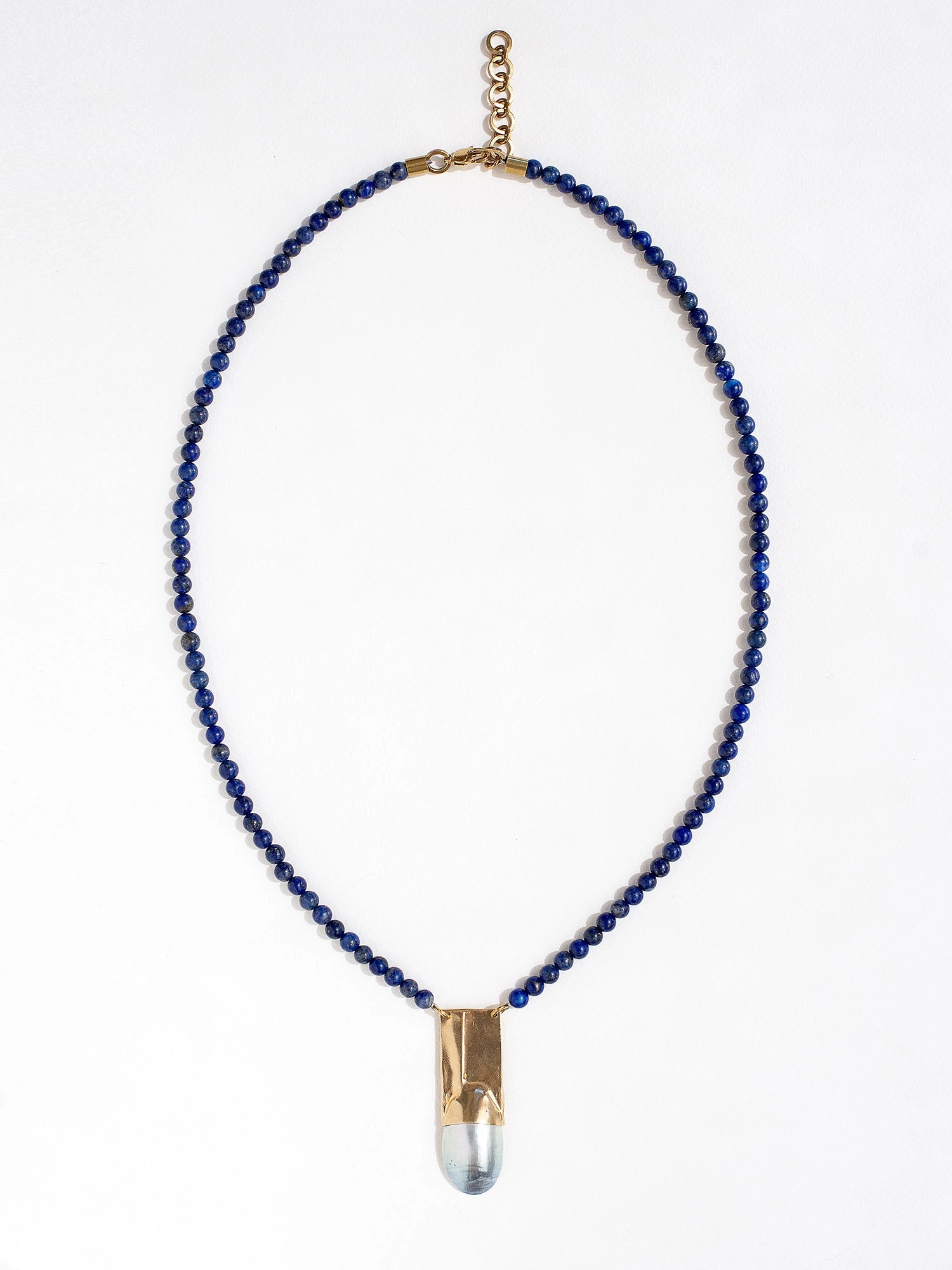 A lapis lazuli beaded necklace with a large statement mother of pearl and brass pendant by Canadian jewellery designer Michelle Ross
