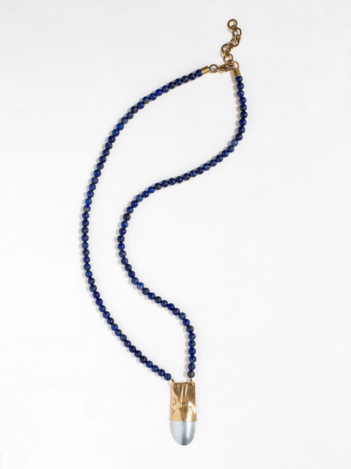 A lapis lazuli beaded necklace with a large statement mother of pearl and brass pendant by Canadian jewellery designer Michelle Ross
