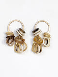 Pair of dangly brass earrings with multiple horn rings in gold, brown, and white