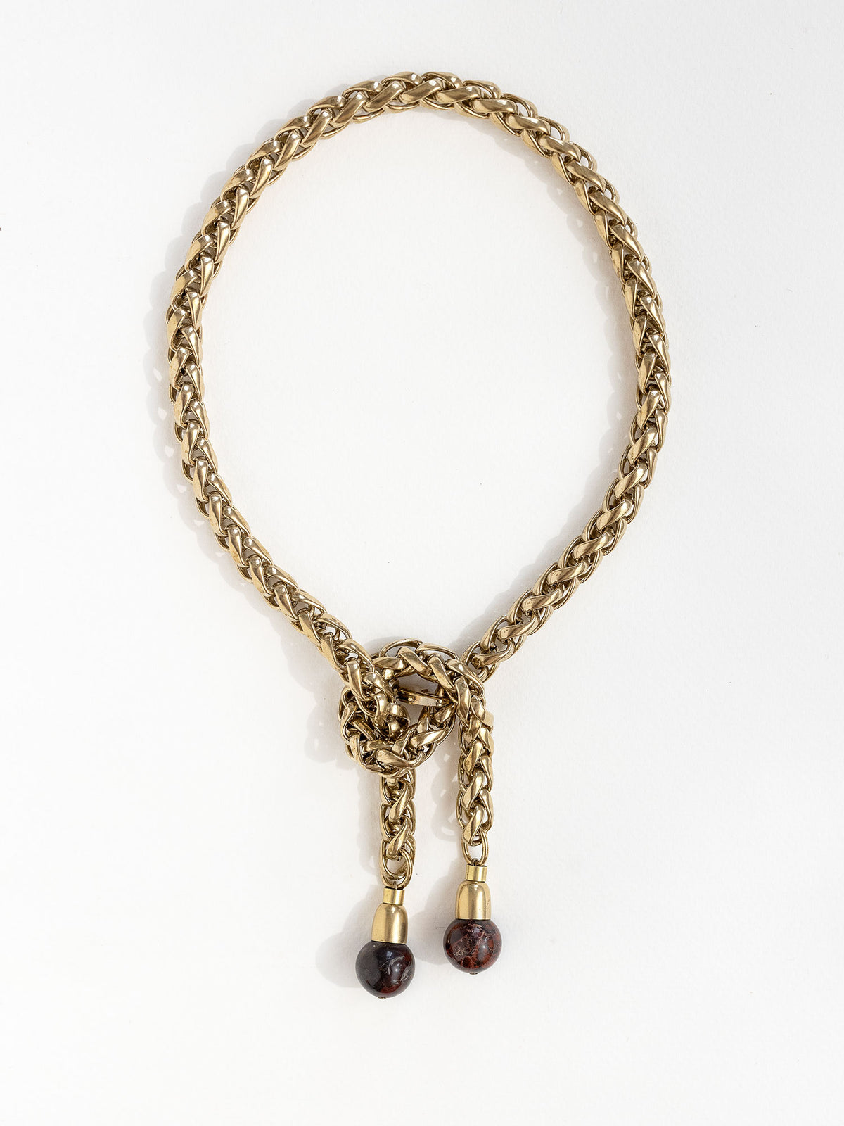 A brass chain lariat necklace with a knotted center detail and two red jasper bead tassels by Canadian jewelry designer Michelle Ross