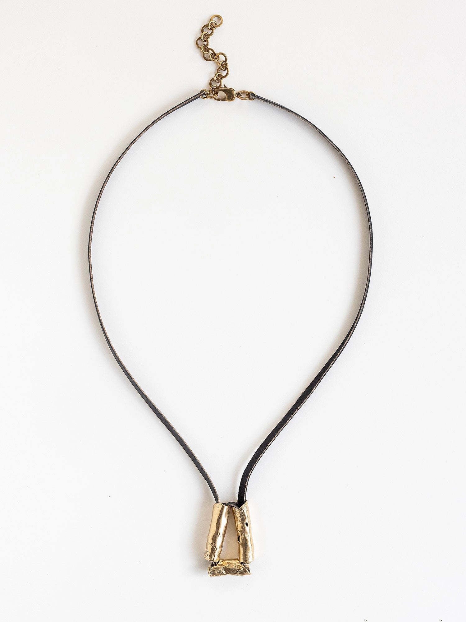 Long black leather necklace with a brass sculptural pendant by Michelle Ross