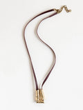 Long burgundy leather necklace with a brass sculptural pendant by Michelle Ross