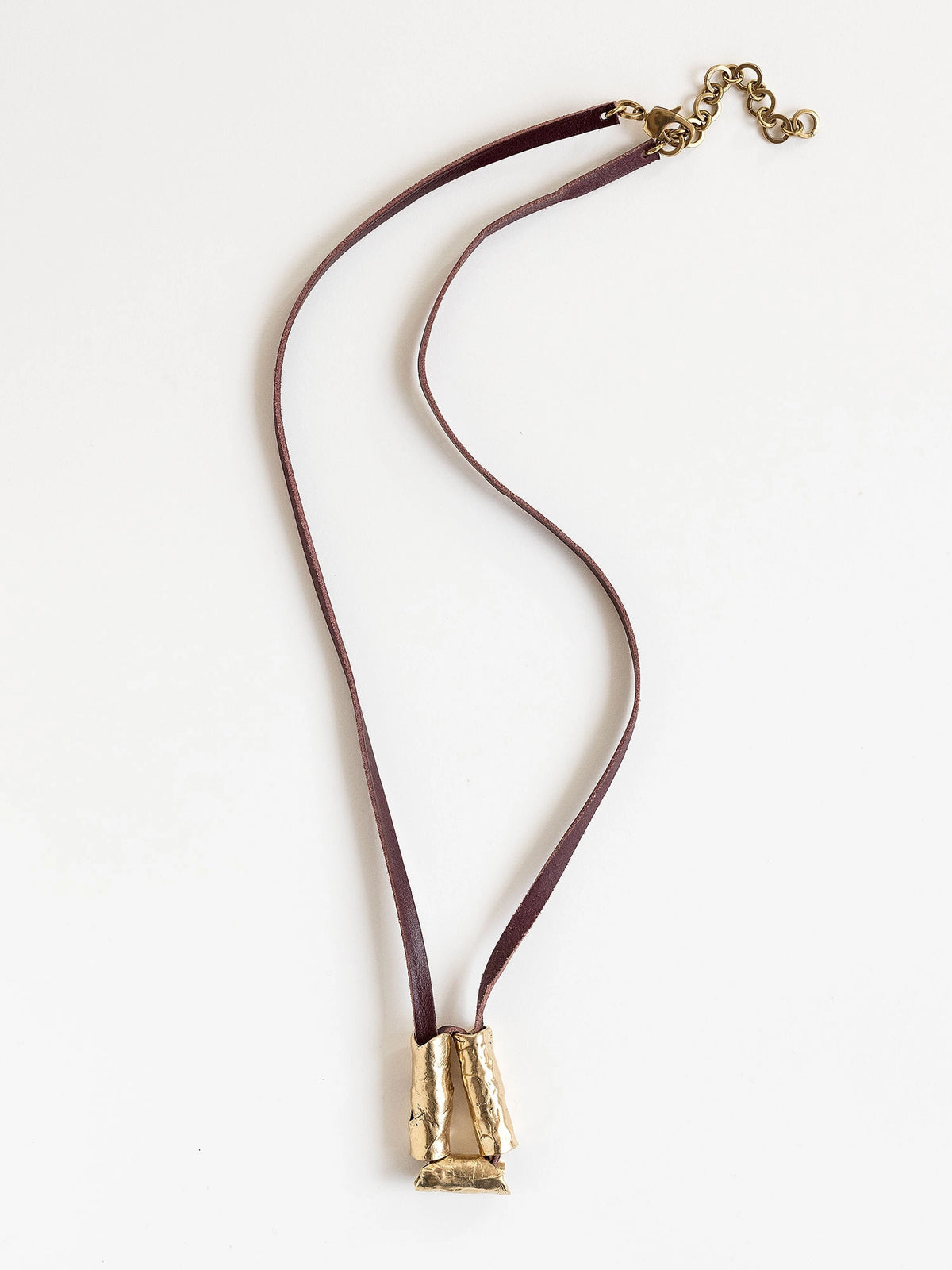 Long burgundy leather necklace with a brass sculptural pendant by Michelle Ross