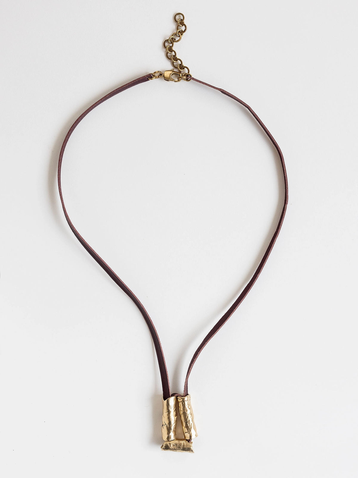 Long burgundy leather necklace with a brass sculptural pendant by Michelle Ross