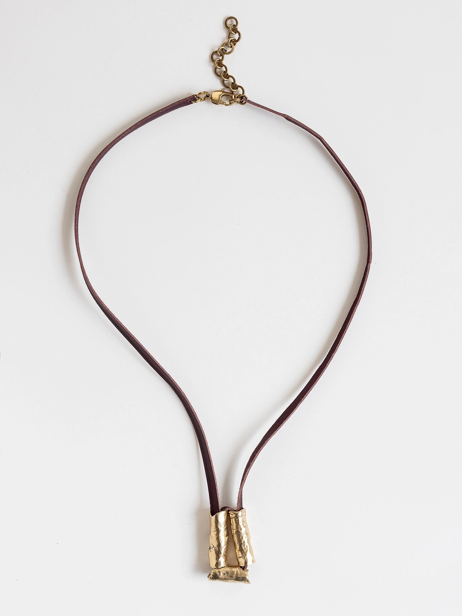 Long burgundy leather necklace with a brass sculptural pendant by Michelle Ross